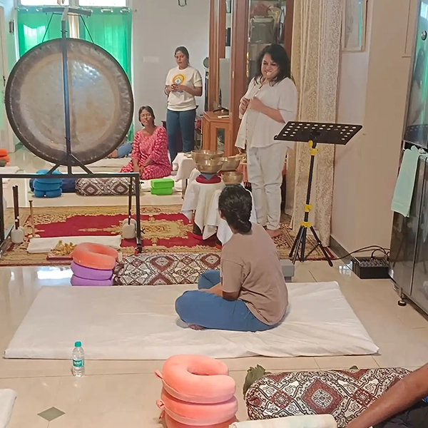 Participants relaxing in a restorative yoga class with sound healing instruments in Chennai.