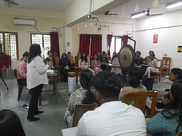 Instructor conducting a sound healing session with gong at University of Madras in a group setting.